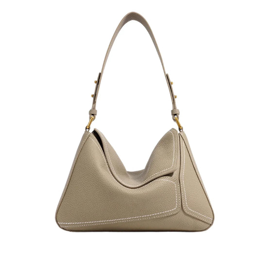 Beige leather shoulder bag with top handle, white stitching, gold hardware on white background
