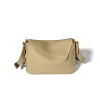 Beige leather crossbody bag with geometric stitching and adjustable strap on white background