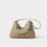 Taupe leather shoulder bag with gold hardware on neutral background