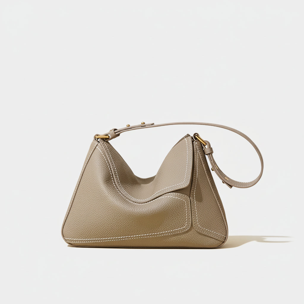 Taupe leather shoulder bag with gold hardware on neutral background