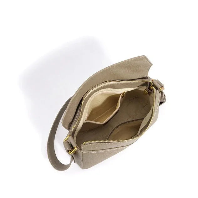 Top view of beige leather crossbody bag with open zipper and multiple compartments