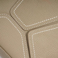 Close-up of beige pebbled leather with white contrast stitching on a luxury bag