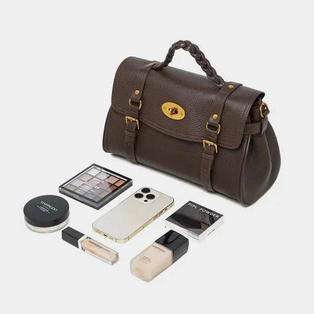 Brown leather handbag with makeup, smartphone, and accessories on white background