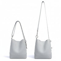 Light gray leather bucket bag with two adjustable shoulder straps on white background
