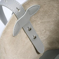 Close-up of beige suede shoe with light gray leather strap and stitched details