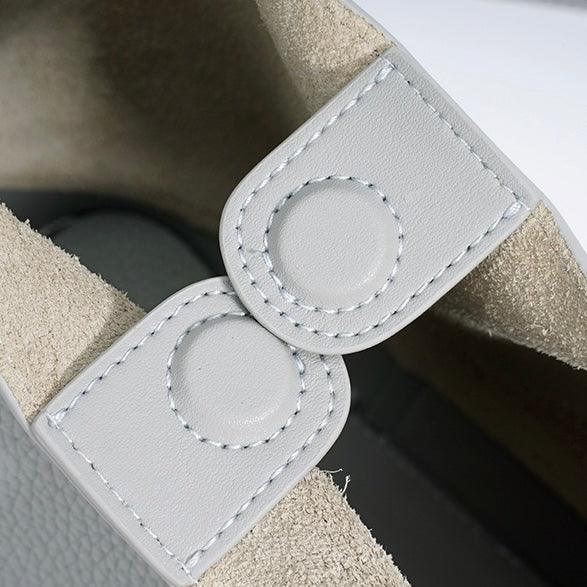 Close-up of white leather shoe with suede lining and double-stitched snap detail