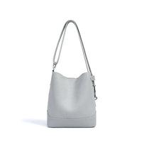 Light grey leather bucket bag with long shoulder strap on white background