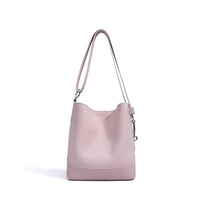 Light pink leather bucket bag with shoulder strap on white background