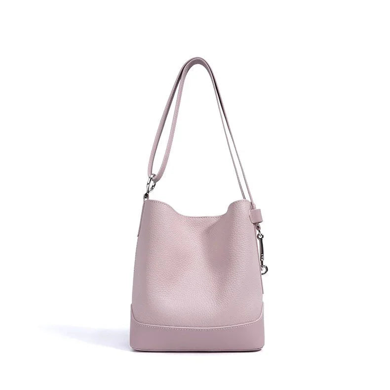 Light pink leather bucket bag with shoulder strap on white background