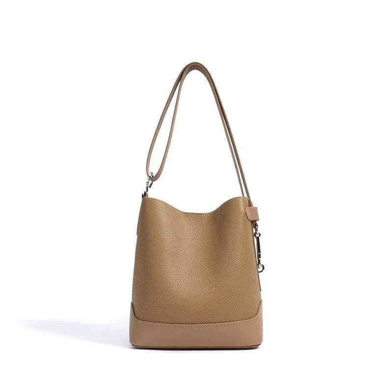 Tan leather bucket bag with shoulder strap on white background