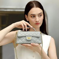 Woman holding a quilted gray handbag with gold chain and clasp, fashion accessory