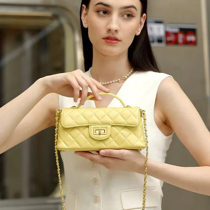 Woman holding yellow quilted leather handbag with gold chain strap, fashion accessory