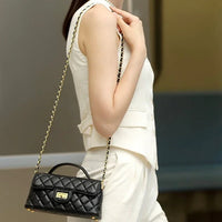 Woman wearing sleeveless white suit with black quilted leather handbag and gold chain strap