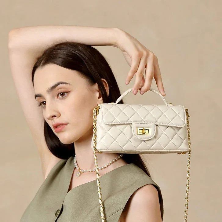 Woman modeling a quilted cream leather handbag with gold chain strap