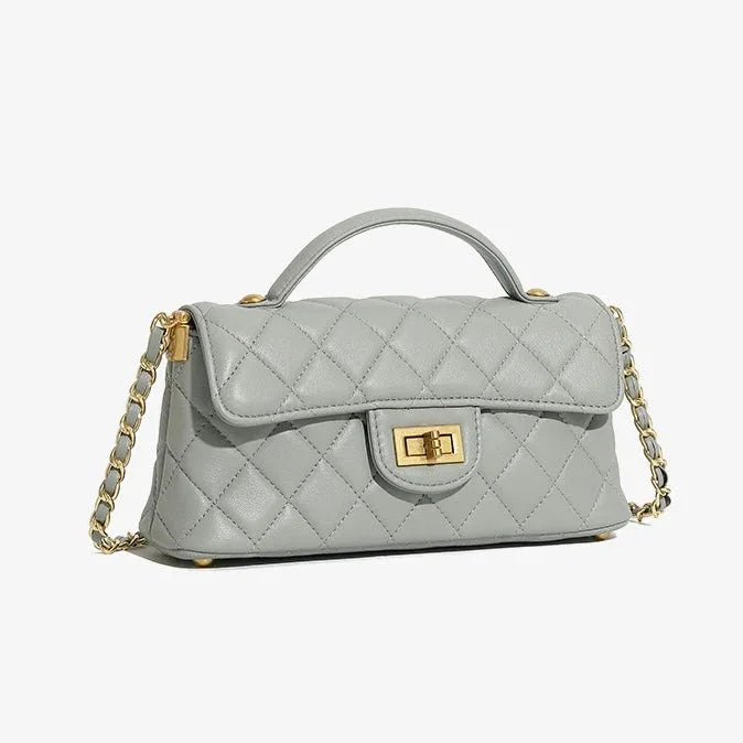 Quilted light gray leather handbag with gold chain strap and turn-lock clasp on white background