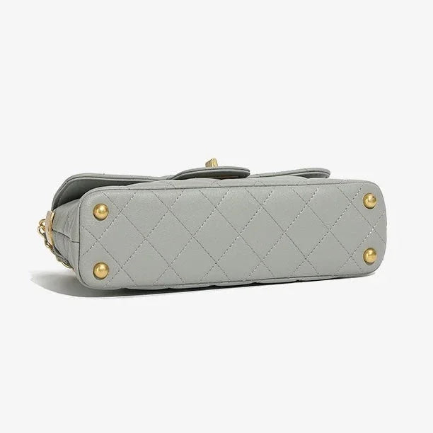 Gray quilted leather handbag bottom with gold studs on white background