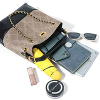 Beige and black quilted handbag with chain strap, yellow umbrella, smartphone, sunglasses, tablet, lipstick, and round cosmetic jar on white background