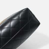 Black quilted leather handbag bottom on white background, luxury purse texture detail
