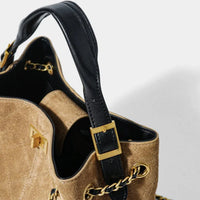 Tan suede handbag with black leather strap and gold chain hardware on white background