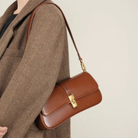 Brown leather shoulder bag with gold clasp on herringbone coat
