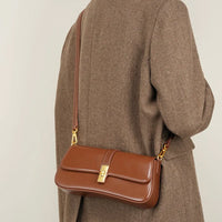 Brown leather shoulder bag with gold clasp on person in herringbone coat