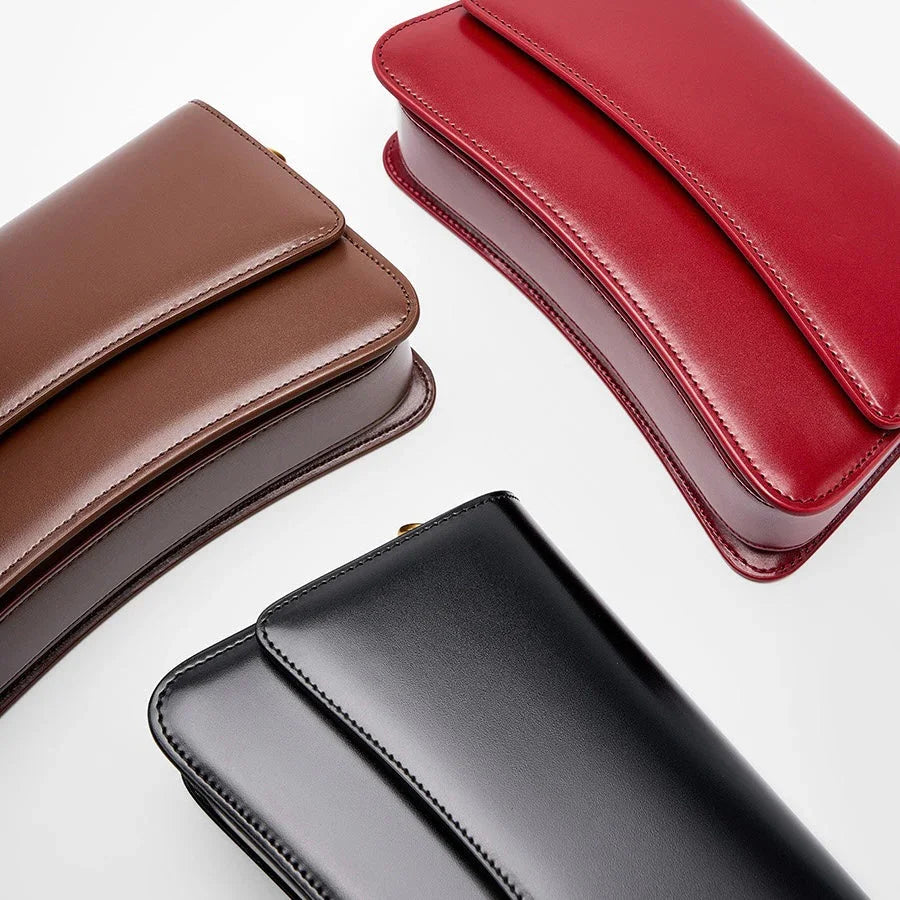 Three rectangular leather handbags in brown, red, and black on a white background