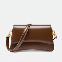Brown leather crossbody bag with gold hardware on a white background