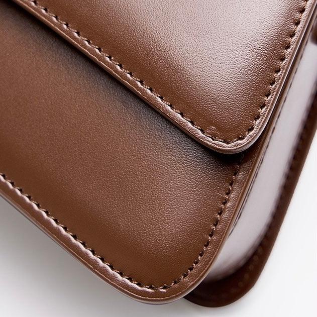 Close-up of brown leather bag with detailed stitching on a smooth surface
