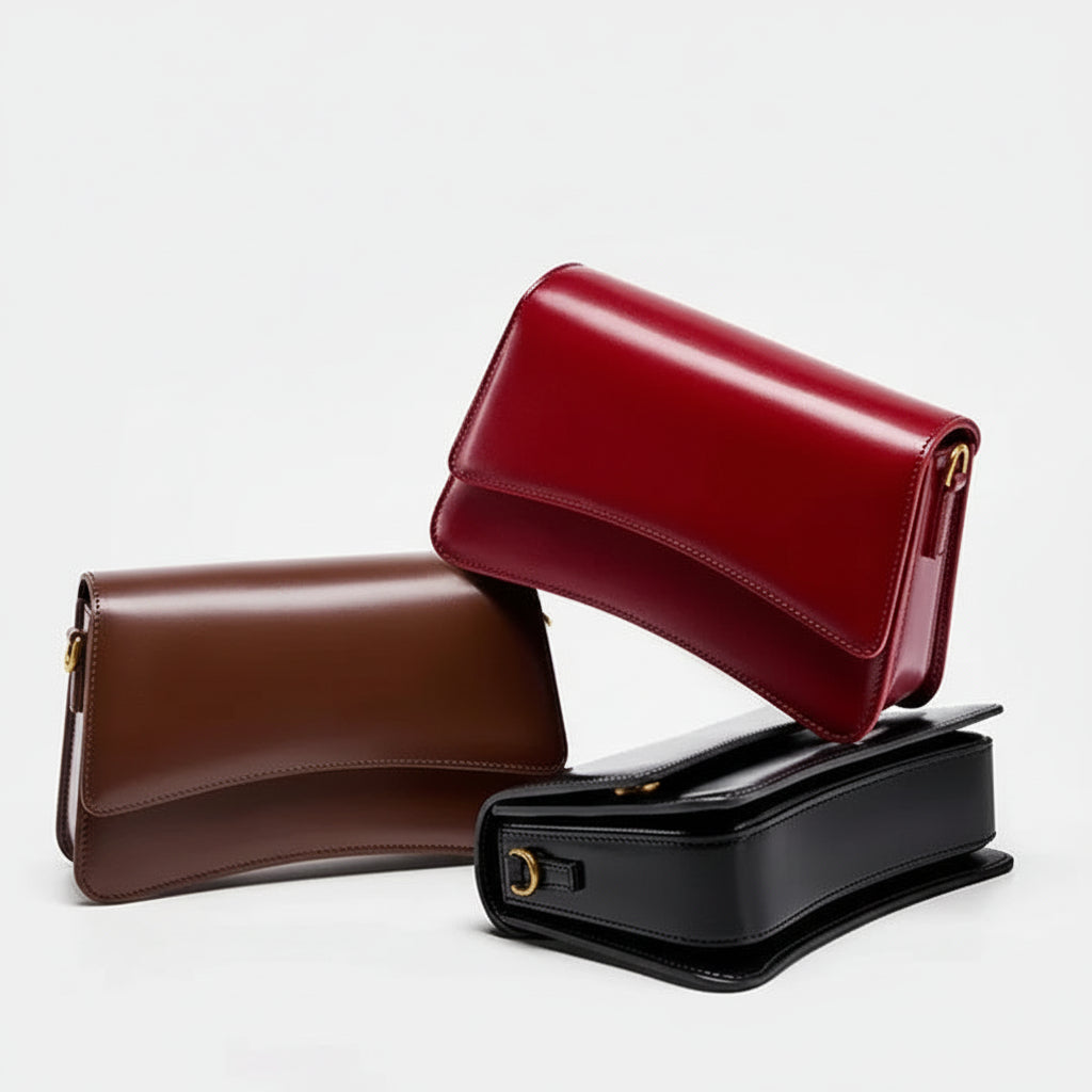 Red, brown, and black leather handbags stacked on a white background