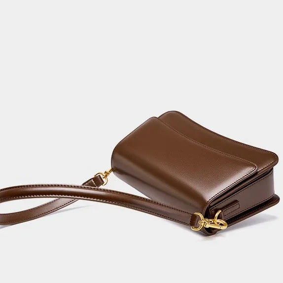 Brown leather crossbody bag with gold hardware on a white background