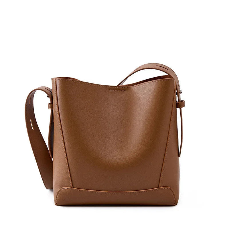 Brown leather bucket bag with adjustable strap on white background