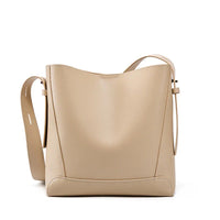 Beige leather shoulder bag with adjustable strap on white background