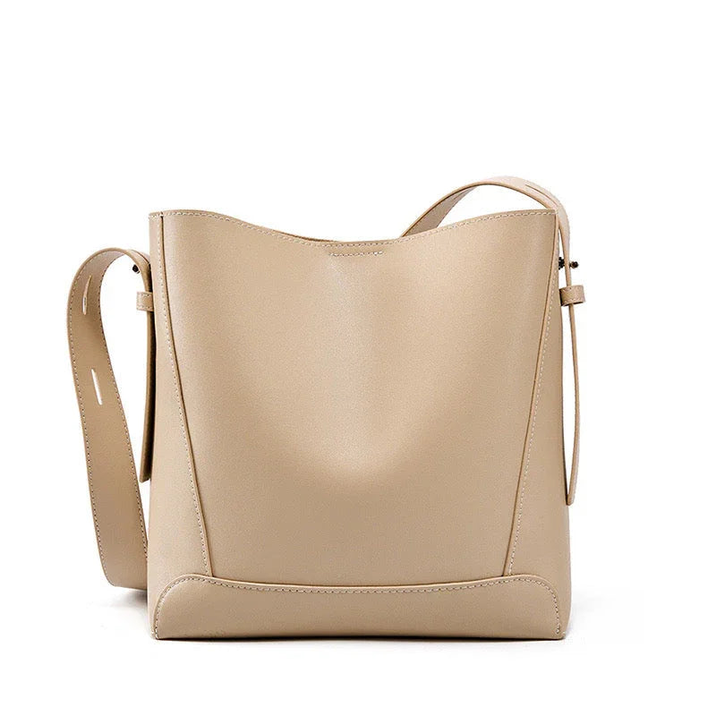 Beige leather shoulder bag with adjustable strap on white background