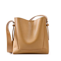 Tan leather bucket bag with adjustable shoulder strap on white background