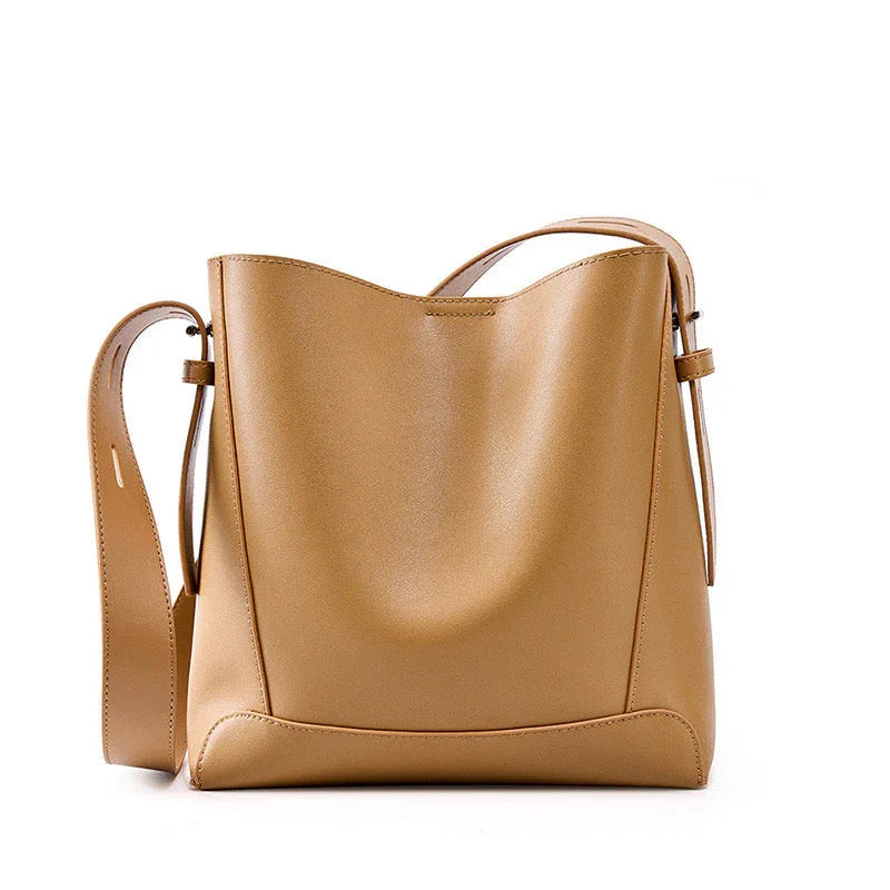 Tan leather bucket bag with adjustable shoulder strap on white background