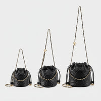 Three black quilted leather bucket bags with gold chain straps on white background