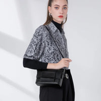 Woman wearing lace blouse and black crossbody bag in minimalist studio