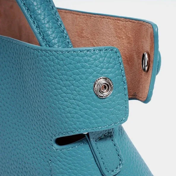 Close-up of blue leather handbag with textured finish and silver snap button