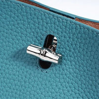 Close-up of silver turn-lock clasp on textured blue leather bag