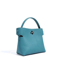 Teal textured leather handbag with top handle and silver clasp on white background