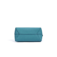 Blue leather handbag with geometric stitching on white background