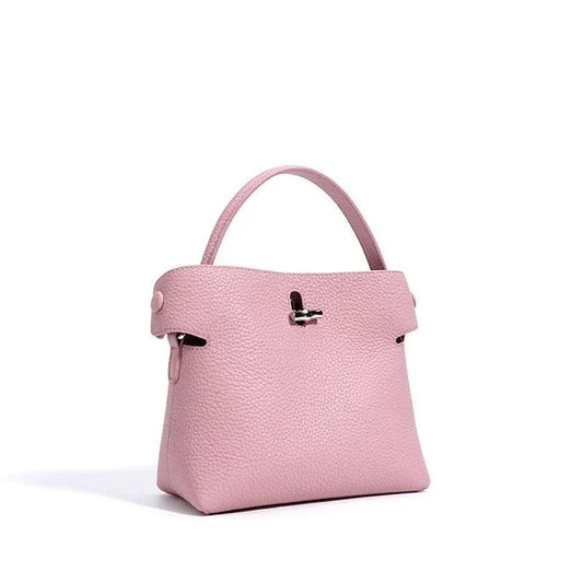 Light pink textured leather handbag with top handle on white background