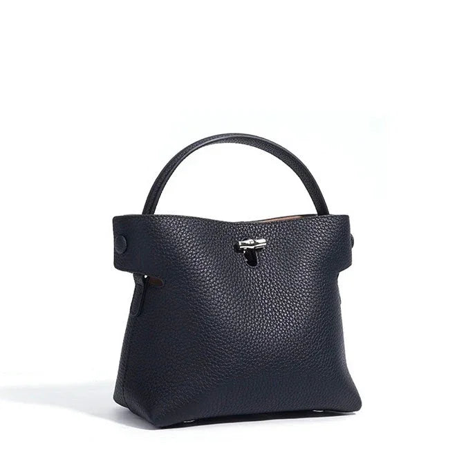 Black textured leather handbag with top handle and silver clasp on white background