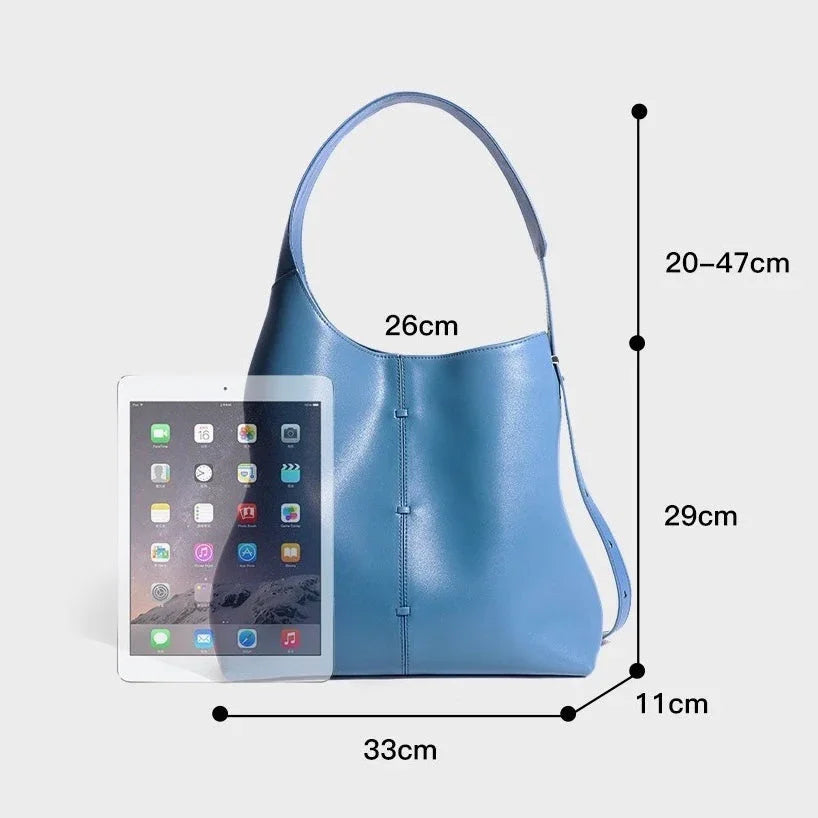Blue leather tote bag with handle, next to tablet, size dimensions in centimeters shown
