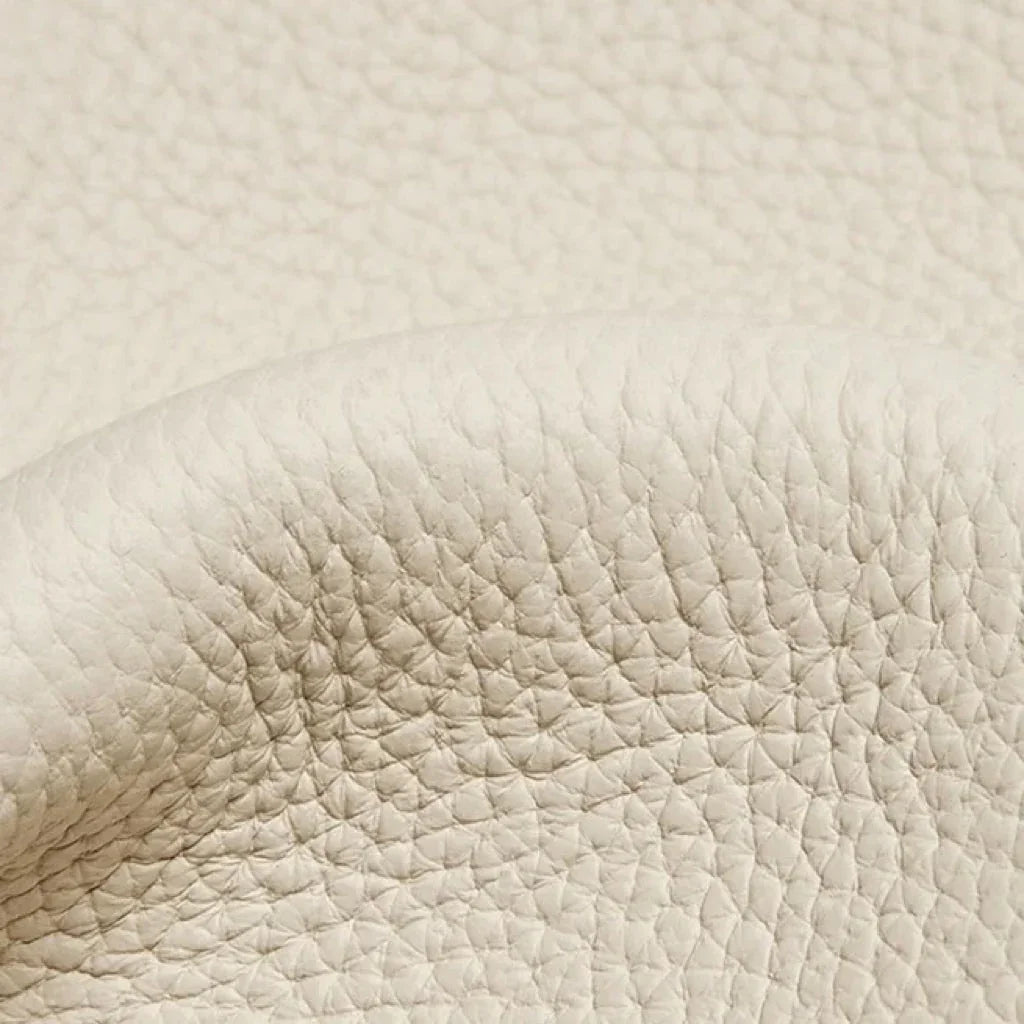 Close-up of textured cream pebbled leather surface, luxury material detail