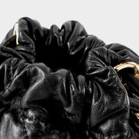 Black leather ruched bag with gold hardware, close-up on gathered drawstring opening