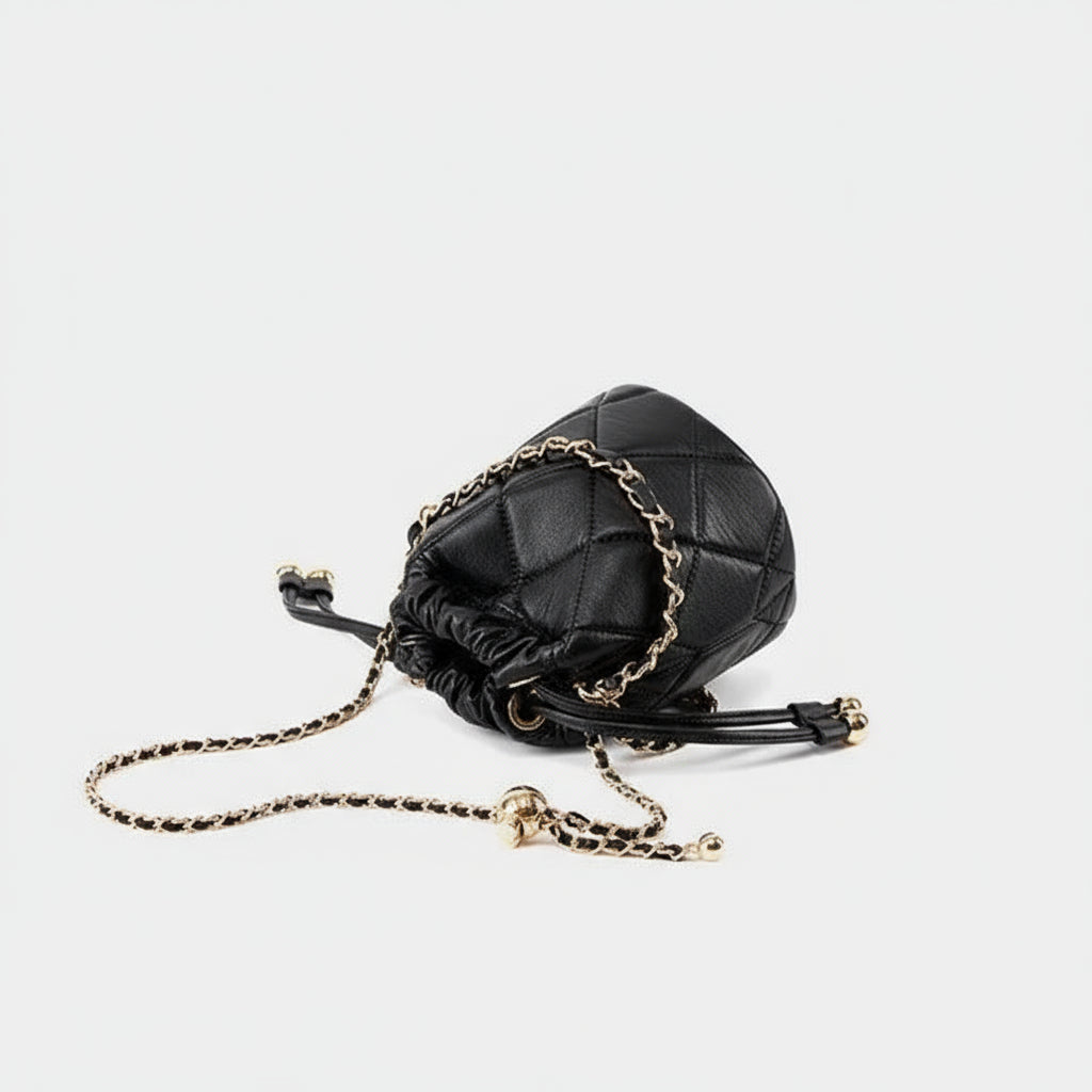 Black quilted leather bucket bag with gold chain strap on white background
