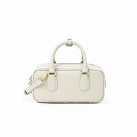 Beige rectangular leather handbag with gold hardware and top handles on white background