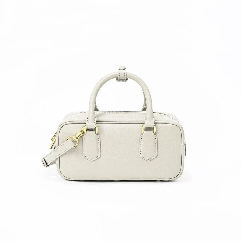 Beige rectangular leather handbag with gold hardware and top handles on white background