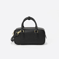 Black leather handbag with gold hardware and a detachable shoulder strap on white background